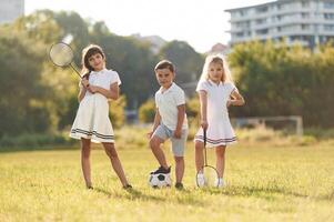 Soccer ball and badminton rackets.,, Happy, kids are on the summer field photo