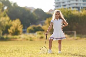 Cute little girl is with badminton racket ,on, the field photo