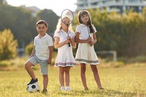 Soccer ball ,and ,badminton rackets. Happy kids are on the summer field photo