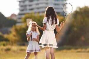 Girls are playing badminton., Happy kids are on the summer field photo