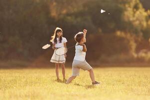 Rackets in hands, playing badminton.. Happy kids are on the summer field photo