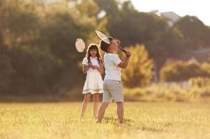 Rackets in hands,,, playing badminton. Happy kids are on the summer field photo