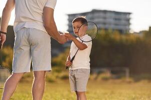 With ,badminton rackets.. Father and little son are together on the summer field photo