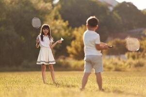 Rackets ,in ,,,hands, playing badminton. Happy kids are on the summer field photo