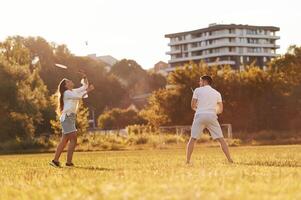 Side view. .,Man with woman are playing badminton on the field photo