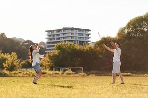 Side view... Man with woman are playing badminton on the field photo
