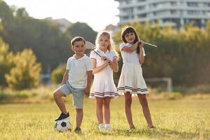 Soccer, ball and badminton rackets. Happy kids are on the summer field photo