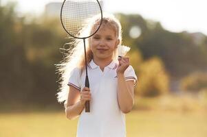 Cute ,little girl is with badminton racket on the field photo
