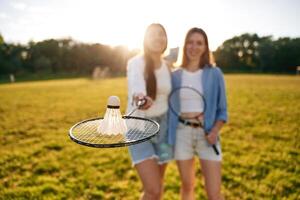 Shuttlecock is on the badminton, racket. Two women are having fun, on the field photo