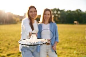 Shuttlecock is on ,the badminton racket. Two women are having fun, on the field photo