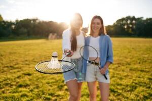 Shuttlecock is ,on the badminton racket. Two women are having fun, on the field photo