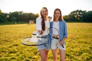 Shuttlecock is ,,on the badminton racket. Two women are having fun, on the field photo