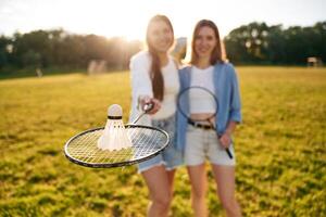 Shuttlecock, is on the badminton racket. Two women are having fun, on the field photo