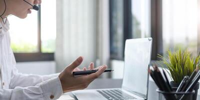 Focused young businessman manager wearing headset with microphone, involved in distant online meeting with colleagues or partners, discussing working issues using call computer application. photo
