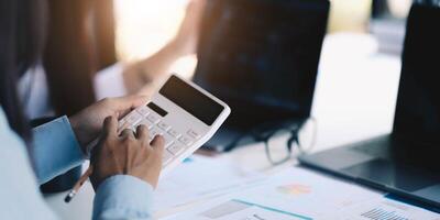 Group businessman hand using calculator Calculating bonus to employees to increase productivity.Writing paper on desk.Selective Focus photo