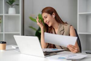 Work Online and Virtual Meetings. A young professional engages in a call, expressing joy and excitement while reviewing documents. photo
