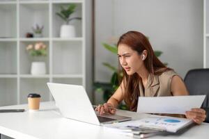 Work Online and Problem Solving. A young professional appears focused and concerned while navigating complex documents in a remote setting. photo
