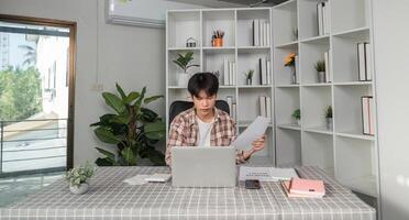 Young financial professional analyzing documents and calculating budget in a modern workspace photo