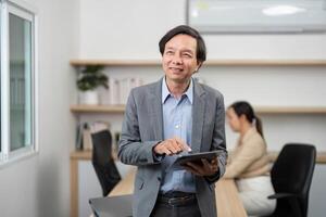 Engaged Businessman with Tablet. Professional man smiling while using a tablet in a modern office. photo