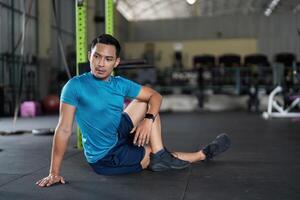 Fitness and Recovery. Man in a seated position on gym floor, preparing for stretching. photo