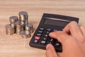A man's hand calculating costs, investment, or money using a calculator on his desk photo