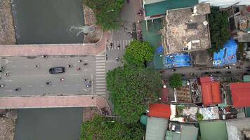 Aerial top-down view of bridge crossing canal and connecting to colorful busy street in Hanoi, Vietnam. Perfect for urban, infrastructure, and Southeast Asia travel themes video