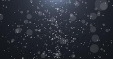 Slowly falling, swirling, and sparkling bokeh particles in white light against a dark background. Abstract snow. video
