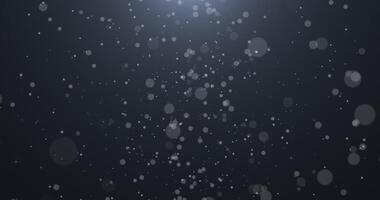 Slowly falling, swirling, and sparkling bokeh particles in white light against a dark background. Abstract snow. 42 video