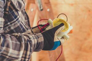 Technician Measures Electrical Current With a Multimeter in a Construction Setting During Daylight Hours photo