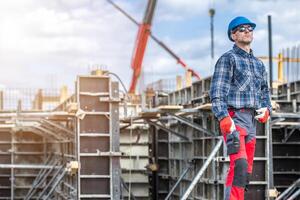 Construction Worker Overseeing Building Project While Wearing Safety Gear and Monitoring Activity at Construction Site During Daytime photo