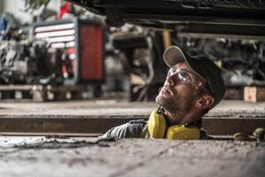 Worker Inspecting Machinery in a Workshop During Daylight Hours photo