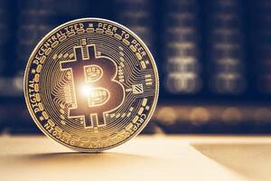 Bitcoin Coin Resting on a Table With Blurred Background of Cryptocurrency Exchange Data photo