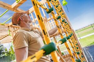 Worker Inspects Climbing Structure at Playground Construction Site in Bright Daytime photo