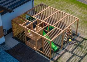 Wooden Playground Structure With Slide and Climbing Features in Sunny Backyard Setting for Children photo