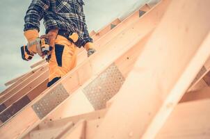 Construction Worker Using Power Tool on Roof During Daylight at a Building Site in a Residential Area photo