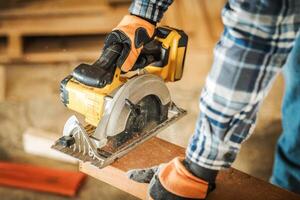 Skilled Carpenter Using Circular Saw for Precise Wood Cutting in Workshop During Daylight photo