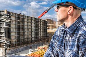 Construction Worker Overseeing the Foundation Work at a Building Site on a Clear Day With Clouds in the Background photo