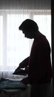 man ironing clothes in front of a window video