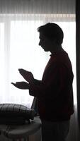 Silhouette of a man praying in front of a window video