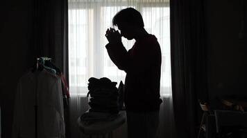 A man standing in front of a window with clothes on his ironing board video
