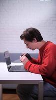 A man photographer with camera sitting at a table with a laptop video