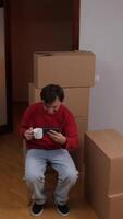 man resting, sitting on a chair with boxes around him video