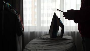 A person silhouette is using a cell phone to look at a iron, man chatting on a phone video