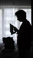 A man ironing clothes in front of a window video