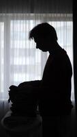 A silhouette of a man standing in front of a window, pile of a laundry video
