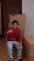 man sitting on a chair with cardboard boxes around him video