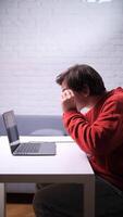 A man sitting at a table with a laptop video