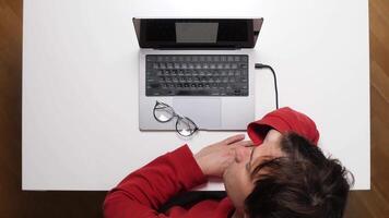 A person sleeping on a table with a laptop video