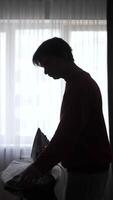 A silhouette of a man ironing clothes video