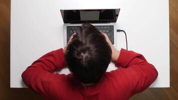 A person sitting at a table with a laptop video